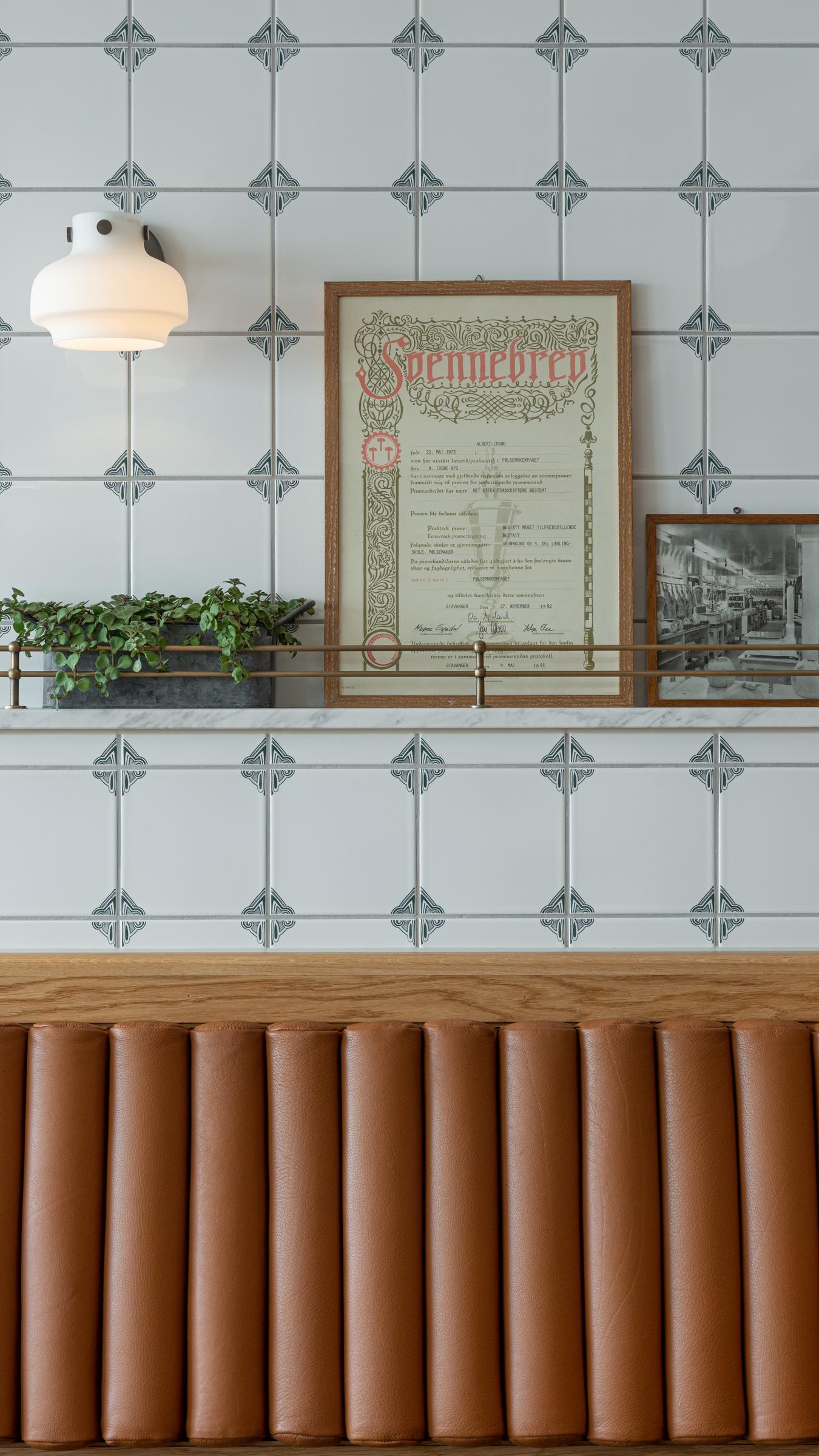Detaljbilde fra sittebenk og vegg i restaurant. Fliser, tre og skinn. Foto 