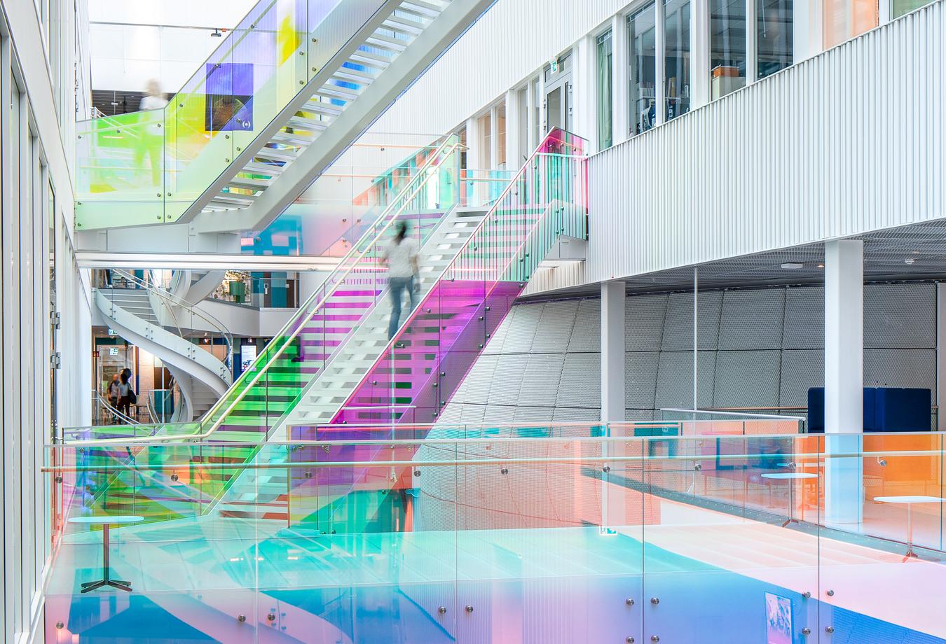 Atrium med trapper i ulike vinkler og glade farger. Foto