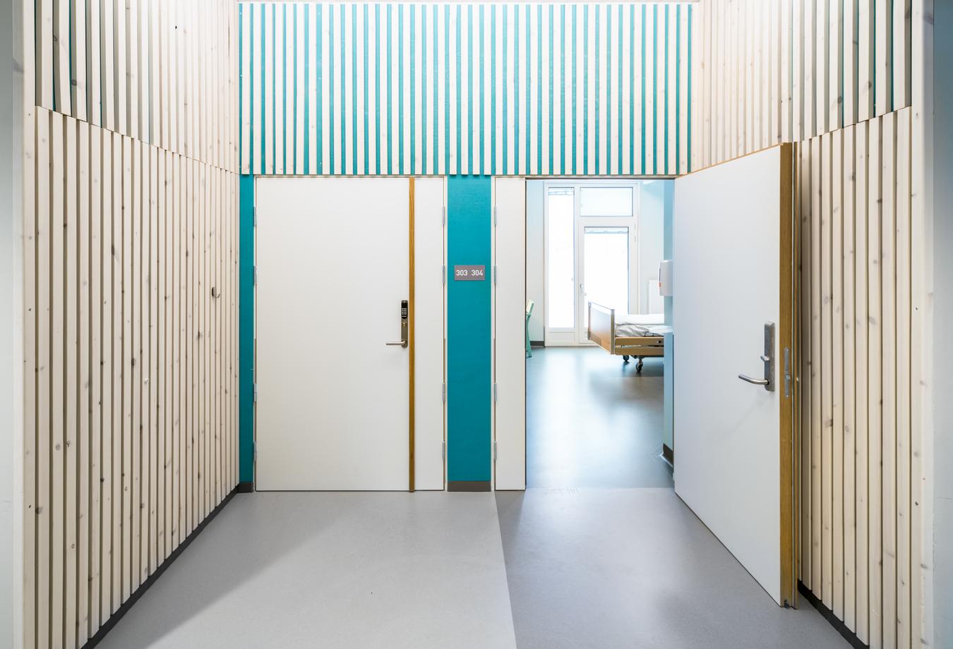Hospital corridor with wooden pillars and turquoise details. Photo